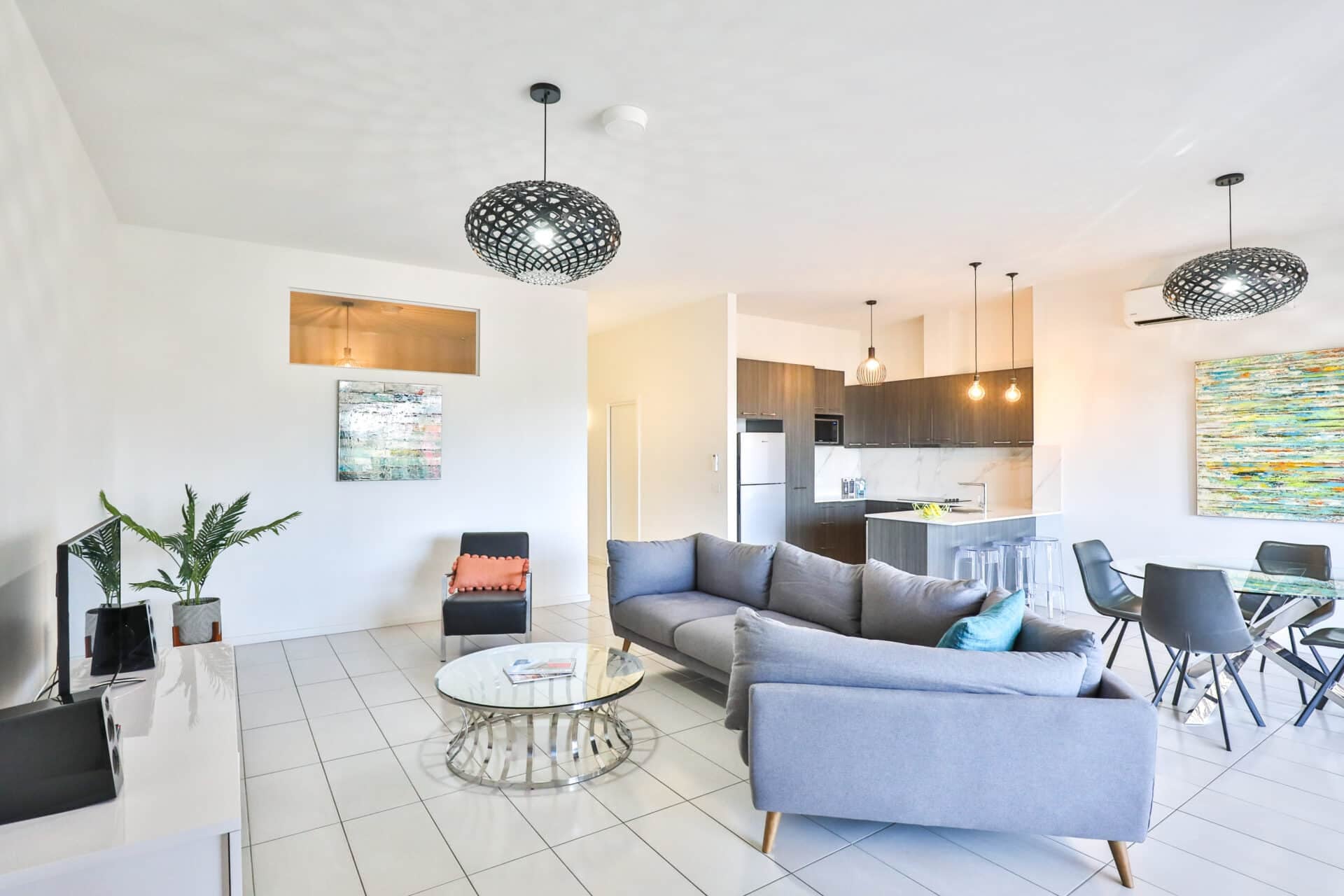 Bright modern open-plan living room and kitchen with gray sectional sofa.